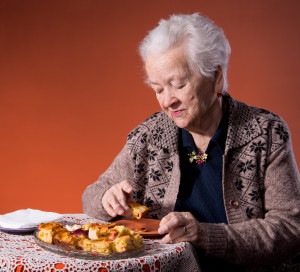 Senior woman tasting apple pie on an orange background