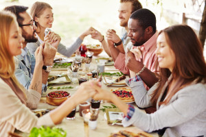 Group of young friends praying at Thanksgiving table